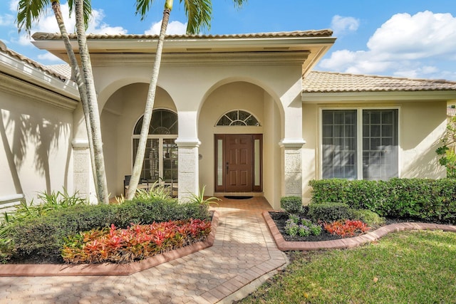 property entrance featuring a tiled roof and stucco siding