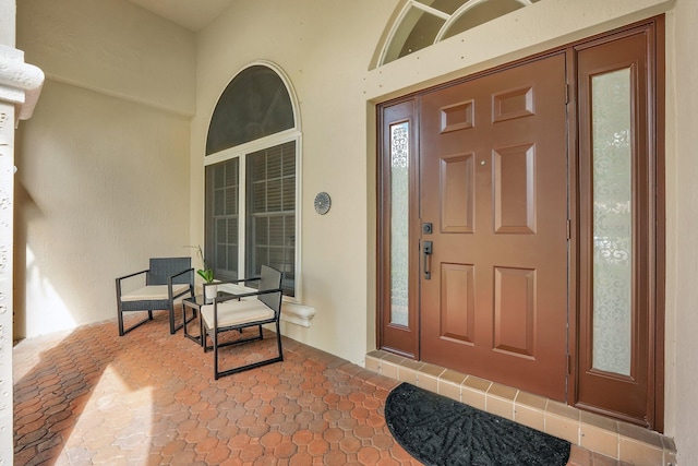 doorway to property with covered porch and stucco siding