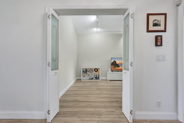 hallway featuring baseboards and light wood-style floors