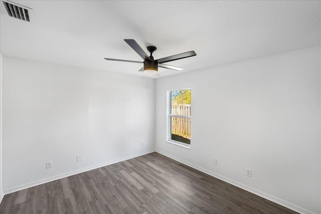 empty room with dark wood-style floors, visible vents, baseboards, and a ceiling fan