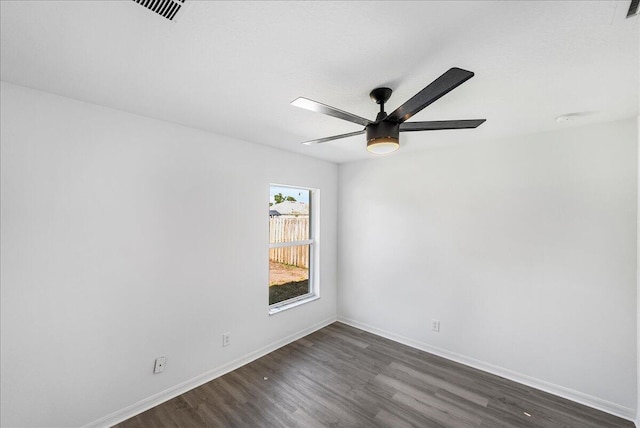 spare room featuring visible vents, baseboards, dark wood finished floors, and a ceiling fan