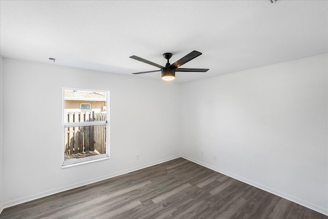 unfurnished room with dark wood finished floors, a ceiling fan, and baseboards