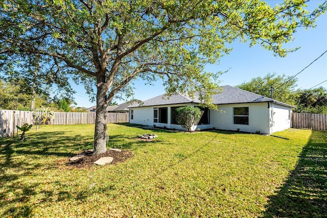 rear view of property featuring a lawn and a fenced backyard