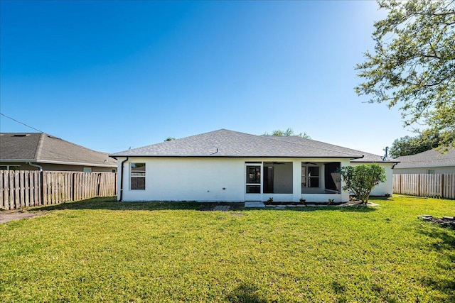 rear view of property with stucco siding, a lawn, a fenced backyard, and a sunroom