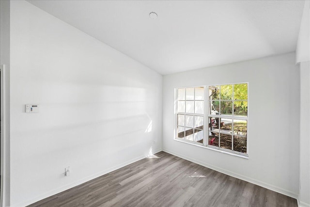 empty room with vaulted ceiling, baseboards, and wood finished floors