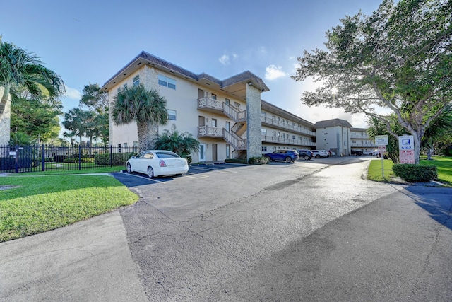 view of building exterior with fence and uncovered parking