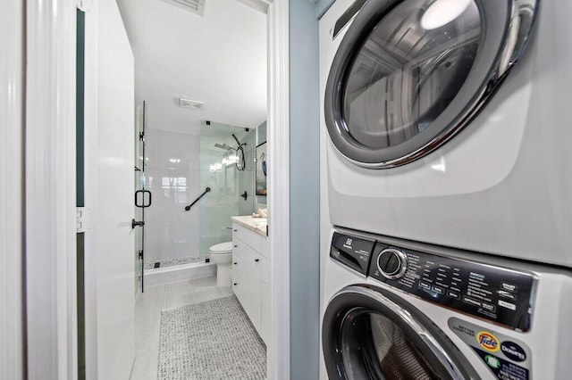 clothes washing area with laundry area, light tile patterned floors, visible vents, and stacked washer and clothes dryer