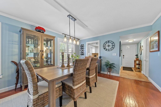 dining room with baseboards, a textured ceiling, wood finished floors, and crown molding