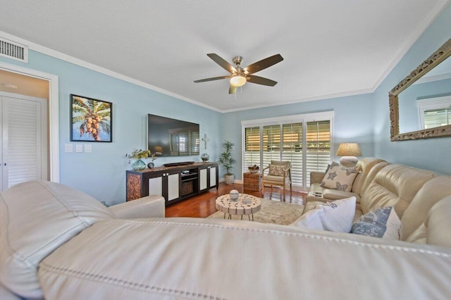 living room featuring visible vents, ornamental molding, a ceiling fan, and wood finished floors