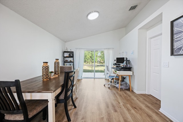 office with baseboards, visible vents, lofted ceiling, light wood-style floors, and a textured ceiling