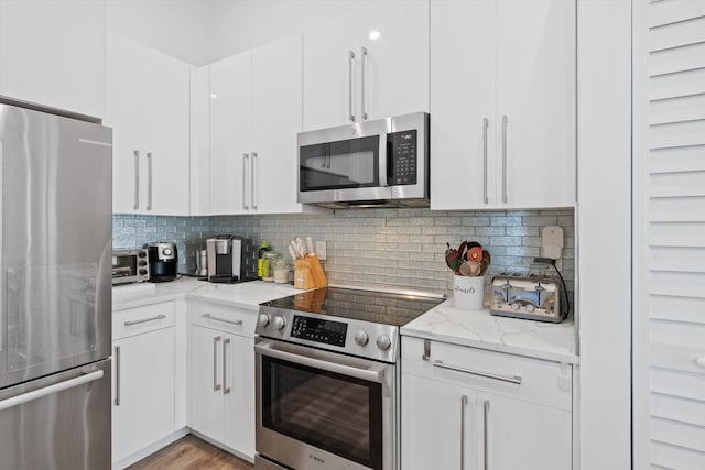 kitchen with white cabinetry, backsplash, and appliances with stainless steel finishes