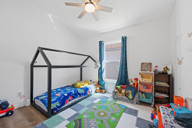 bedroom with a textured ceiling, wood finished floors, a ceiling fan, and vaulted ceiling