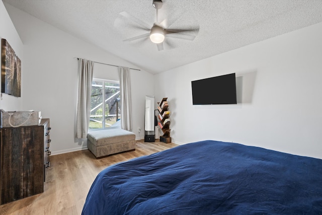 bedroom featuring baseboards, a textured ceiling, lofted ceiling, and wood finished floors