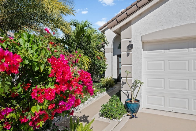 exterior space with stucco siding, an attached garage, and a tiled roof