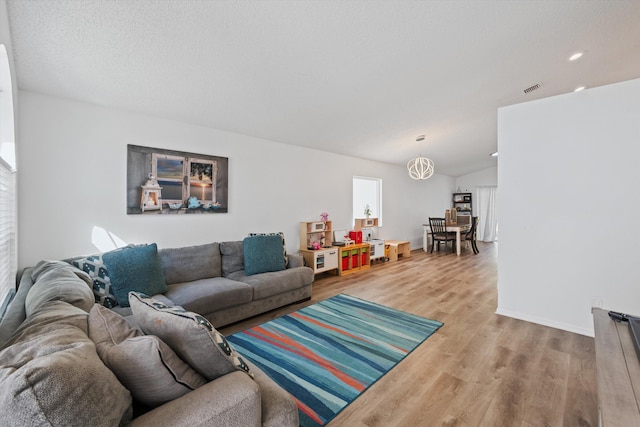 living area featuring visible vents, baseboards, and wood finished floors