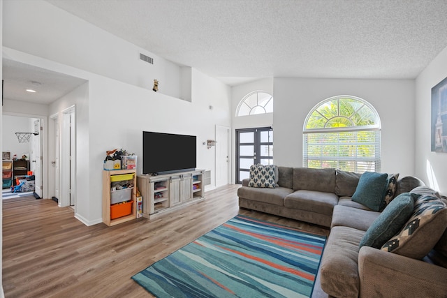 living area with wood finished floors, visible vents, french doors, and a textured ceiling