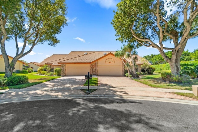 view of front of house featuring driveway, an attached garage, stucco siding, stone siding, and a tiled roof