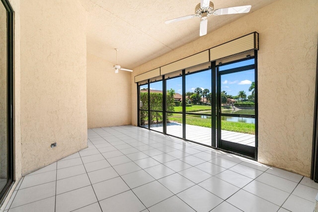 tiled empty room with a ceiling fan, a textured wall, and a water view