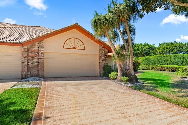 view of front facade featuring stucco siding, concrete driveway, a front yard, a garage, and brick siding