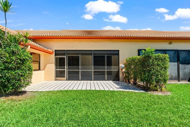 rear view of house featuring a patio, a yard, a tile roof, and stucco siding