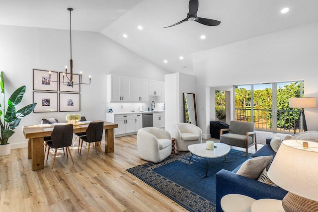 living area with recessed lighting, ceiling fan with notable chandelier, high vaulted ceiling, and light wood-style floors