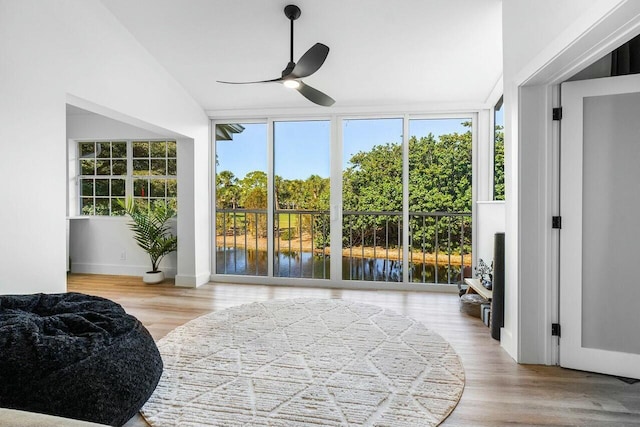 sunroom featuring a water view, lofted ceiling, and a ceiling fan