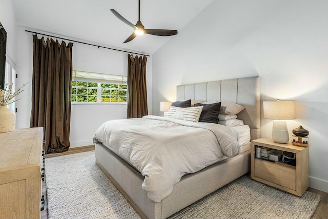 bedroom with light wood-type flooring, baseboards, a ceiling fan, and vaulted ceiling