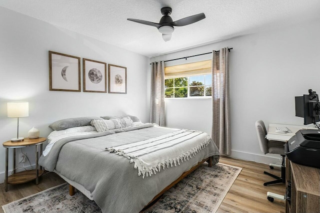 bedroom with a ceiling fan, light wood-style floors, baseboards, and a textured ceiling