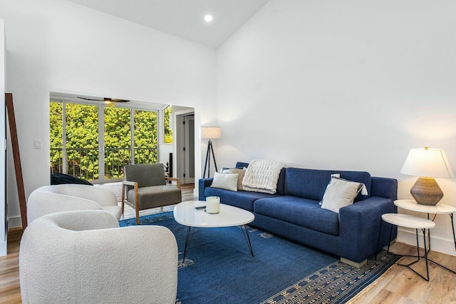 living area featuring recessed lighting, baseboards, wood finished floors, and a towering ceiling