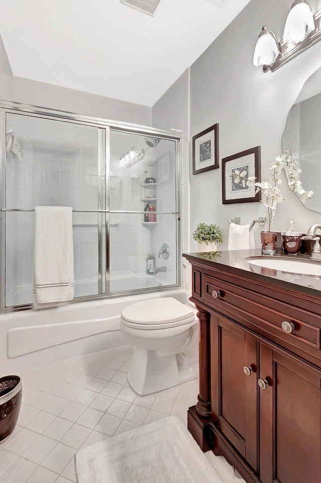 bathroom with tile patterned flooring, toilet, vanity, and shower / bath combination with glass door