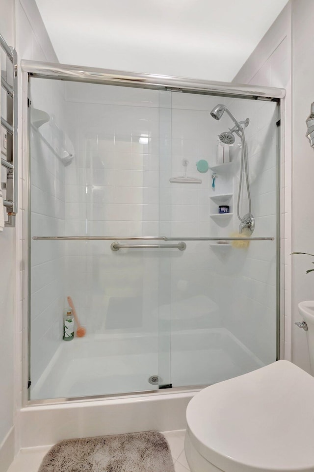 full bath featuring tile patterned floors, a shower stall, and toilet