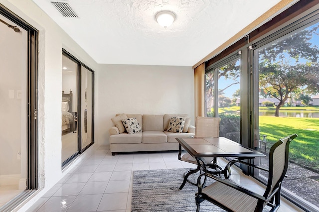 sunroom / solarium with visible vents and a water view