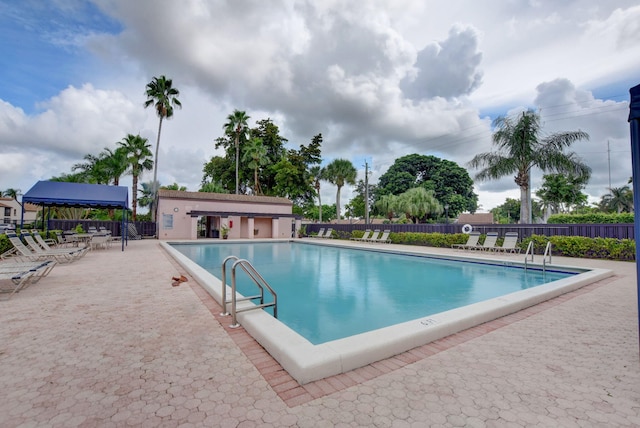 community pool with a patio area and fence