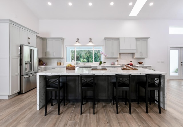 kitchen with a large island, high end refrigerator, gray cabinets, and decorative backsplash