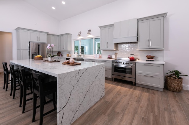 kitchen with a spacious island, tasteful backsplash, custom range hood, premium appliances, and gray cabinets