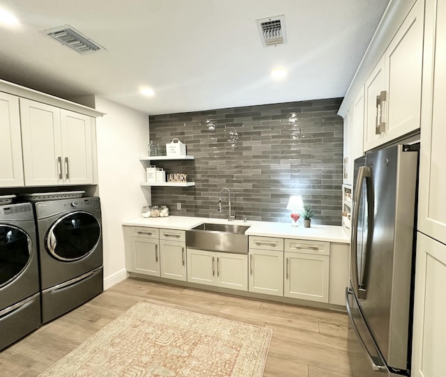 clothes washing area featuring a sink, visible vents, laundry area, and washer and clothes dryer