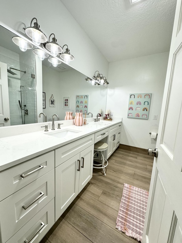 full bathroom featuring a sink, double vanity, wood finished floors, and a shower stall