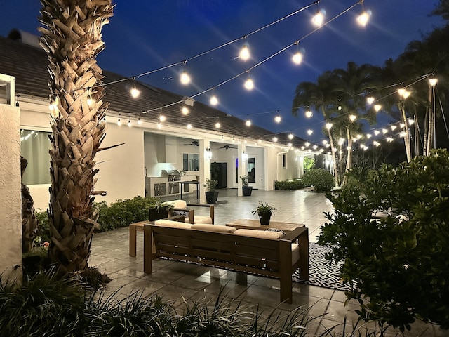 patio at night featuring outdoor lounge area and a ceiling fan