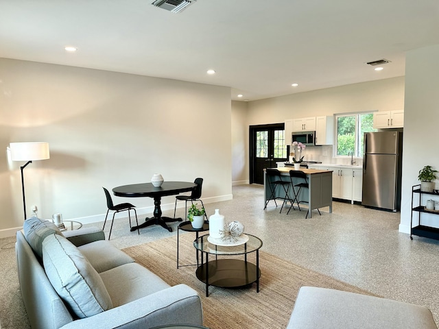 living area with light speckled floor, recessed lighting, visible vents, and baseboards