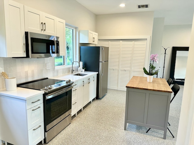 kitchen featuring a sink, butcher block countertops, white cabinets, appliances with stainless steel finishes, and tasteful backsplash