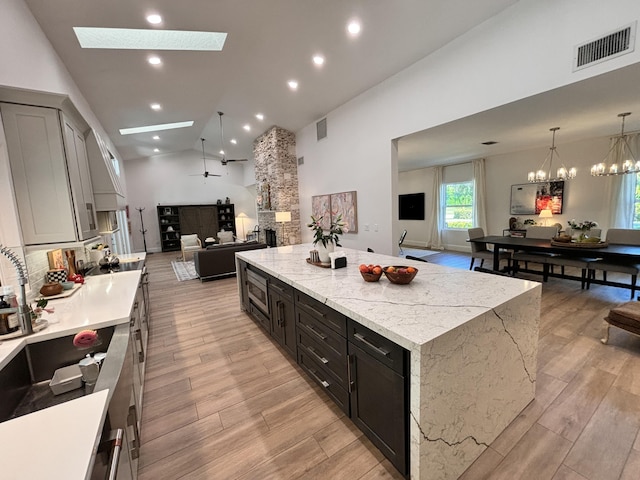 kitchen featuring visible vents, a large island, open floor plan, a skylight, and light wood finished floors