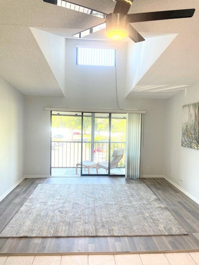 empty room with a textured ceiling, baseboards, and wood finished floors