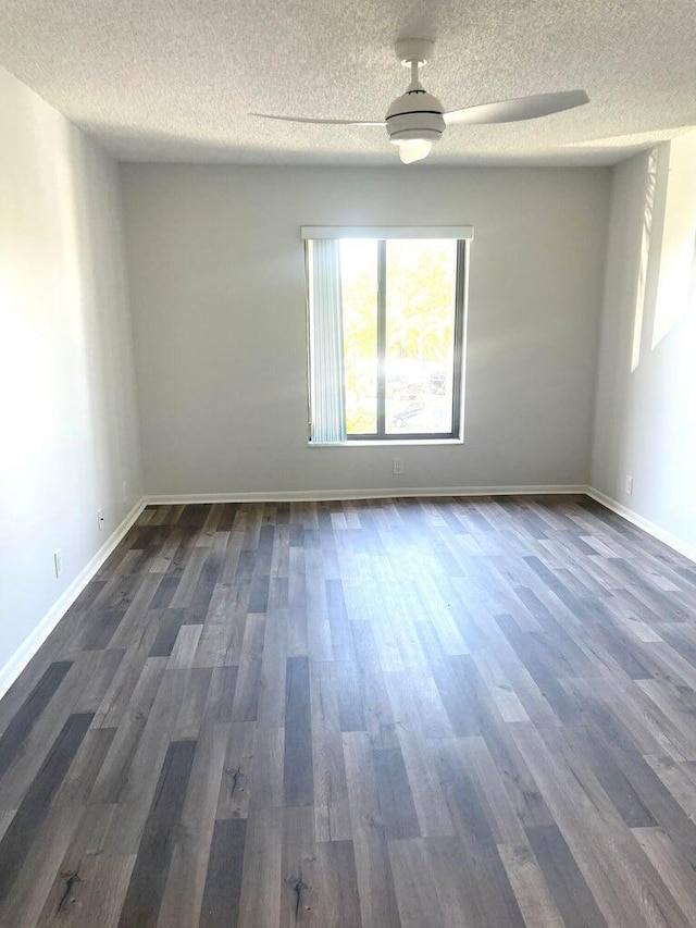 spare room with baseboards, a textured ceiling, and dark wood-style flooring