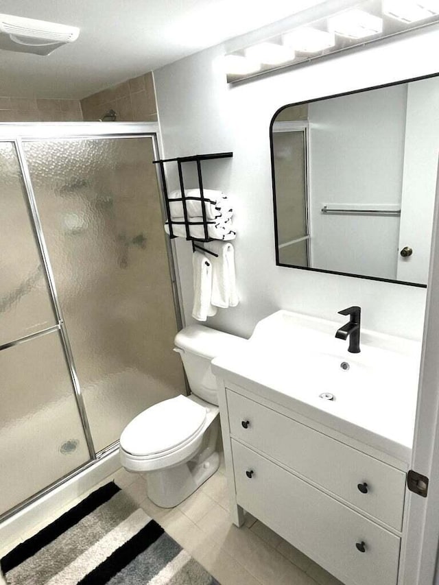 full bath featuring tile patterned flooring, a shower stall, toilet, and vanity