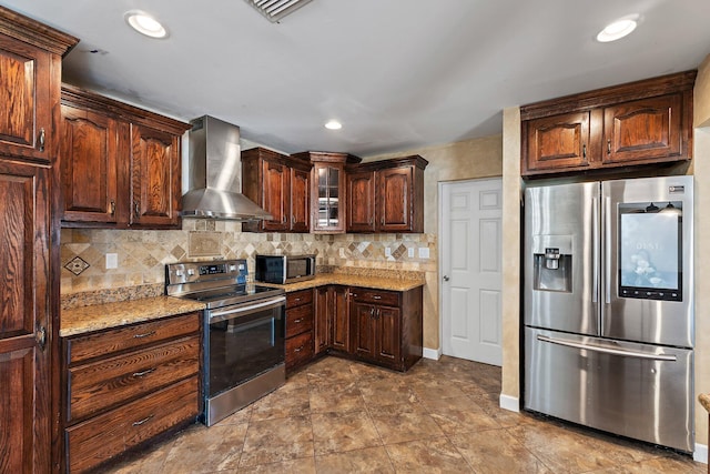 kitchen with decorative backsplash, light stone countertops, appliances with stainless steel finishes, and wall chimney exhaust hood