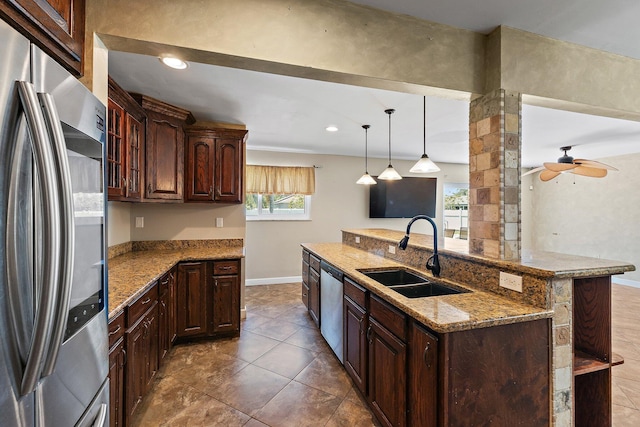 kitchen featuring baseboards, dark brown cabinetry, pendant lighting, appliances with stainless steel finishes, and a sink