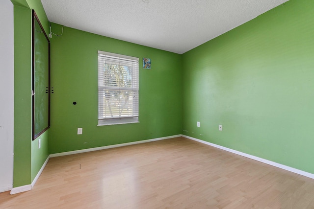 unfurnished room with light wood-type flooring, baseboards, and a textured ceiling