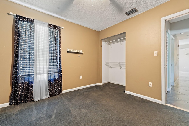 unfurnished bedroom with visible vents, a textured ceiling, carpet flooring, baseboards, and ceiling fan