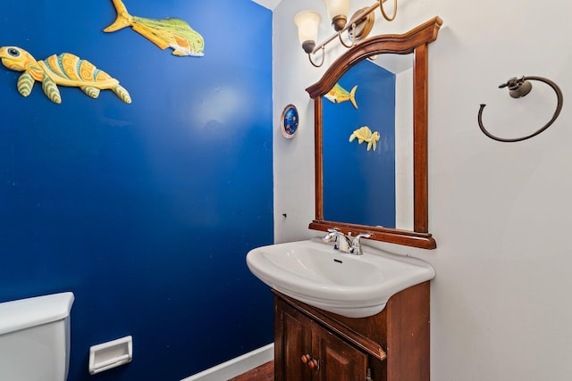 half bath with toilet, vanity, and baseboards