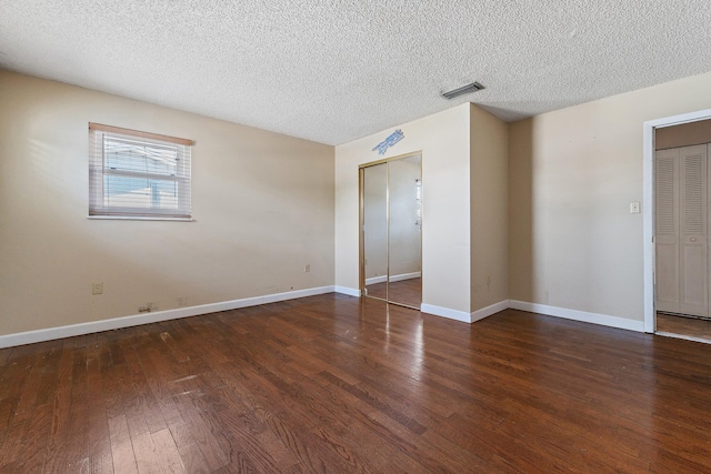 spare room featuring visible vents, a textured ceiling, baseboards, and hardwood / wood-style floors